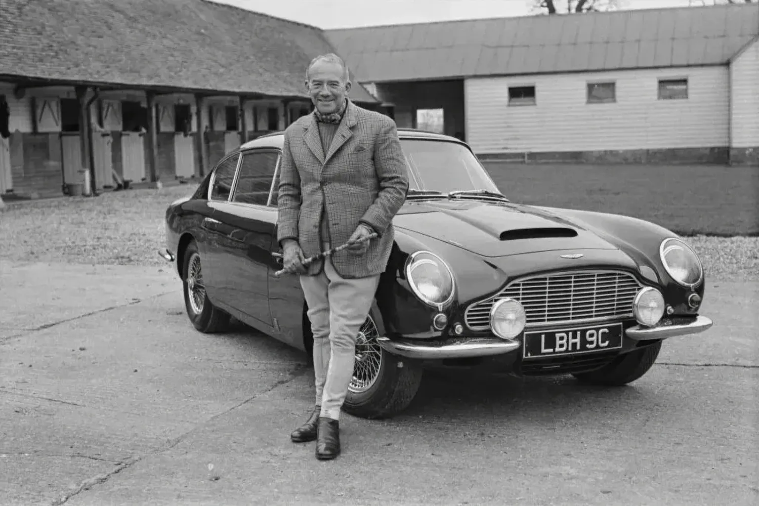 Sir David Brown in front of his Aston Martin DB5 (Image via Insidehook.com)